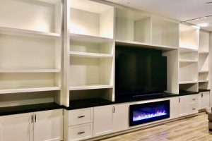 Entertainment - Massive white wall unit with electric fireplace, thick panels and shelves, black countertop and hardware