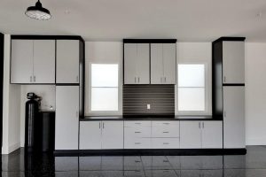 Garage Cabinets - 2 tone black and gray built around windows and water softener